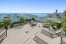Expansive terrace featuring large-format porcelain tile flooring and a transparent glass railing overlooking the coastal skyline and harbor