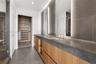Dual-vanity cabinetry featuring wood-finish lower drawers and open shelving, topped with matte stone countertops and integrated rectangular sinks