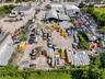 Industrial property featuring a metal-framed arched warehouse structure, expansive open-air storage yard, and perimeter fencing