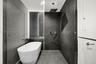 Freestanding soaking tub, large-format dark tile wall surfacing, overhead rainfall showerhead, handheld shower fixture, and frameless glass enclosure