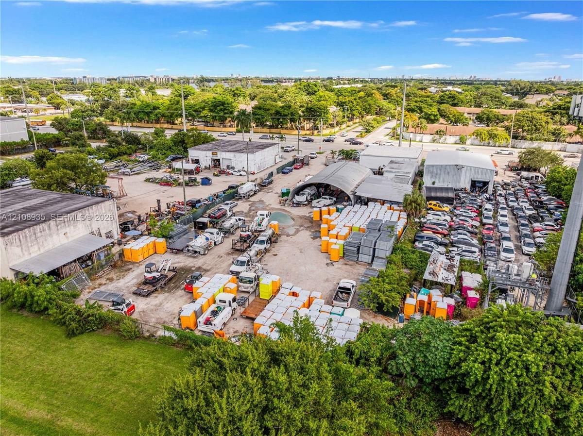Expansive industrial lot featuring multiple commercial warehouse structures, extensive open-air storage space, and perimeter fencing