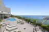 Rooftop terrace featuring an elevated swimming pool, glass panel railing, and light-toned tile flooring