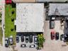 Aerial perspective featuring a commercial structure with an expansive paved surface area, dedicated on-site parking spaces, and manicured green space