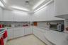 Kitchen featuring floor-to-ceiling white cabinetry, solid-surface countertops, integrated under-cabinet lighting, stainless steel sink with metal fauc