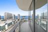 Curved balcony featuring large-format tile flooring and a glass panel railing, framed by floor-to-ceiling glass windows