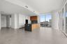 Kitchen featuring flat-panel cabinetry with wood and white finishes, large central island with stone-surface countertop, full-height windows, and tile