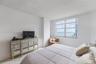 Neutral-toned interior featuring expansive horizontal windows with ocean and coastal horizon scenery, light-colored tile flooring, and textured ceilin