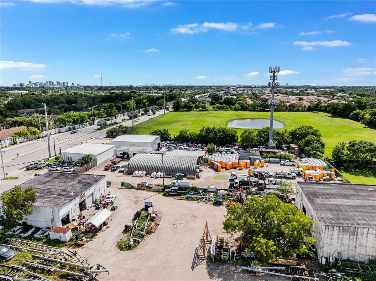 Expansive industrial property featuring multiple detached structures, a metal Quonset-style building, dedicated paved and unpaved storage areas, and d