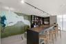 Custom wet bar featuring a solid countertop, integrated shelving, matte black track lighting, and floor-to-ceiling mural