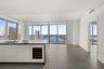 Kitchen island with stone-finish countertop, undermount sink, integrated wine cooler, and expansive floor-to-ceiling windows featuring water scenery
