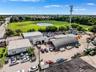 Industrial property featuring multi-structure layout with arched metal storage building, paved surface parking, and extensive open land