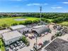 Industrial property featuring multiple structures including a semi-cylindrical metal warehouse, expansive exterior paved lot, and perimeter fencing