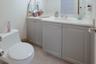 Bathroom vanity featuring soft-gray cabinetry, a white countertop, an integrated oval sink, chrome dual-handle faucet, and large-format tile flooring