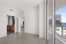 Large-format tile flooring, floor-to-ceiling glass sliding doors, private balcony, and interior doorways with wood-finish cabinetry