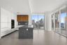 Modern kitchen featuring matte white cabinetry, wood-finish upper cabinets, a dark stone-finish waterfall island, recessed lighting, and floor-to-ceil
