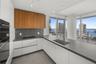 Kitchen featuring wood-finish upper cabinetry, matte white base cabinetry, dark stone-finish countertops and backsplash, stainless steel undermount si