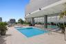 Rooftop terrace featuring an inground pool with built-in lounge ledge, expansive light-toned tile decking, integrated structural pergola, and floor-to