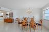 Open-concept living space featuring large-format tile flooring, a decorative crystal chandelier with ceiling medallion, and oversized windows providin