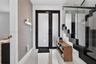 Entryway featuring a black-framed glass entry door, large-format tile flooring, textured wall covering, and a staircase with open risers and a glass r