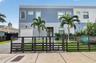 Modern two-story exterior featuring multi-tonal stucco facade, horizontal slat metal fencing, integrated single-car garage, and paved walkway