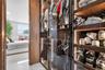 Custom walk-in closet featuring floor-to-ceiling wood-finish cabinetry, glass-front doors, and integrated vertical LED lighting