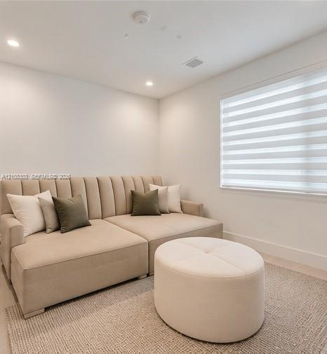 Neutral-toned room featuring recessed ceiling lighting and adjustable window blinds