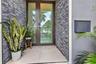 Entryway featuring a full-glass door with dark metal frame, charcoal-toned stacked stone accent walls, large-format tile flooring, and a wall-mounted 