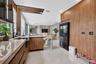 Kitchen featuring wood-finish cabinetry, stone countertops, a deep basin sink with a matte black faucet, integrated full-height cabinetry, and archite