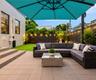 Outdoor patio featuring large-format concrete pavers, tiered stone steps, and a perimeter privacy fence with integrated string lighting