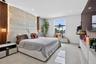 Textured stone feature wall with integrated accent lighting, recessed ceiling lighting, large-format tile flooring, and custom wall-mounted cabinetry