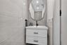 Wall-mounted white vanity with two drawers, rectangular basin, matte black faucet, and large organic-shaped mirror, featuring floor-to-ceiling large-f