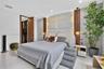 Textured stone accent wall with integrated perimeter lighting, floor-to-ceiling wood paneling, recessed ceiling lighting, and tile flooring