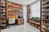 Custom wood-finish cabinetry featuring integrated shelving, built-in desk with drawer storage, glass-front display cases with internal lighting, and l