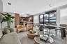 Open-concept interior featuring large-format tile flooring, recessed lighting, wood-finish cabinetry, and sliding glass doors with exterior access