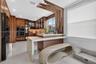 Kitchen featuring custom wood-veneer cabinetry, waterfall-edge stone countertop, integrated double wall ovens, and decorative slatted wood ceiling acc
