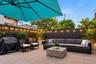 Enclosed patio featuring paved flooring, horizontal metal perimeter fencing, and integrated string lighting