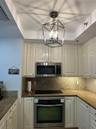 Kitchen featuring white cabinetry, stone countertops, built-in stainless steel oven, integrated microwave, and a geometric metal pendant light