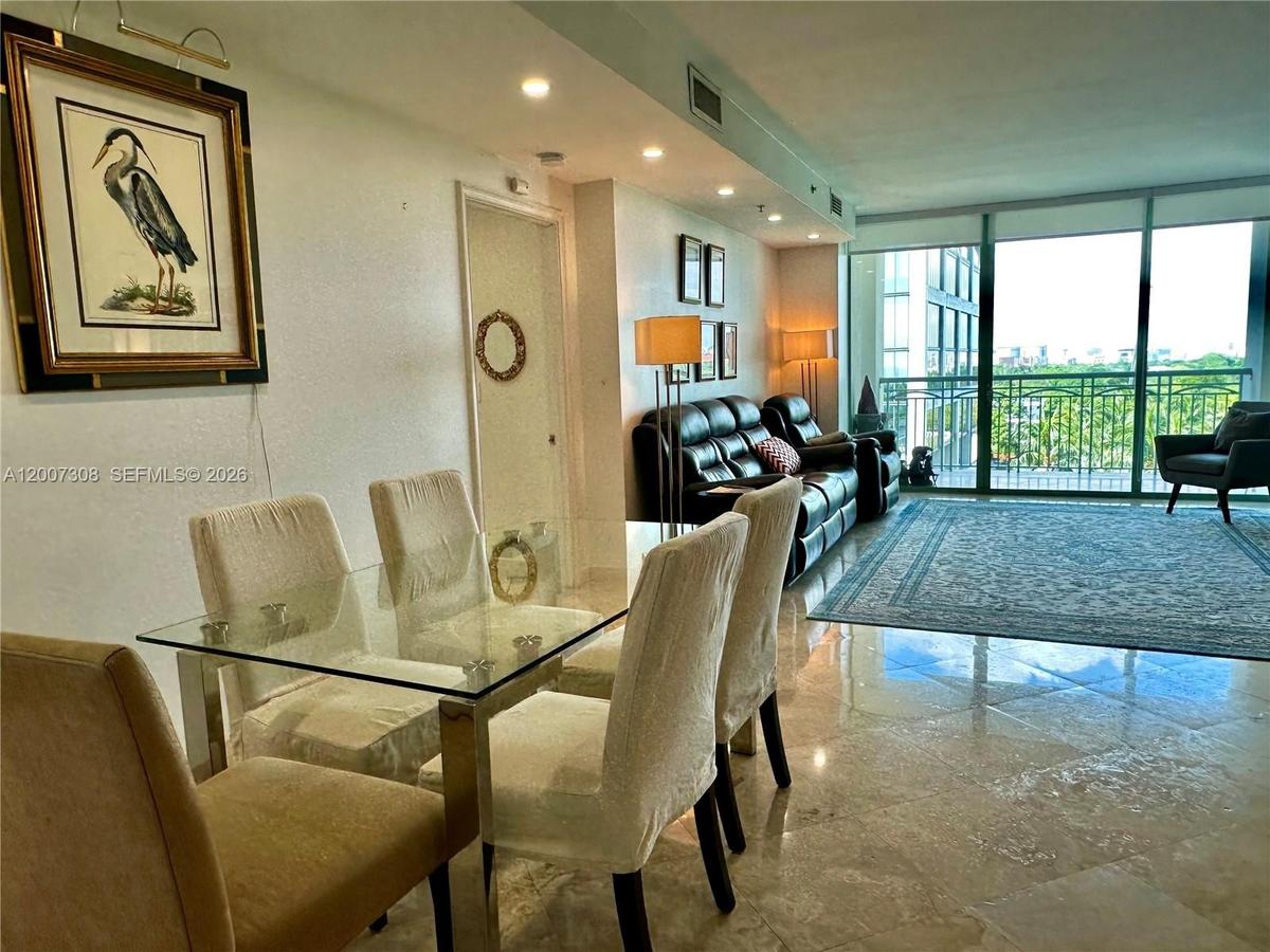 Polished stone flooring, recessed ceiling lighting, and floor-to-ceiling glass paneling with integrated sliding door access to a balcony