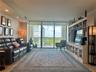 Living area featuring floor-to-ceiling windows, built-in cabinetry, recessed lighting, and a balcony with an iron railing