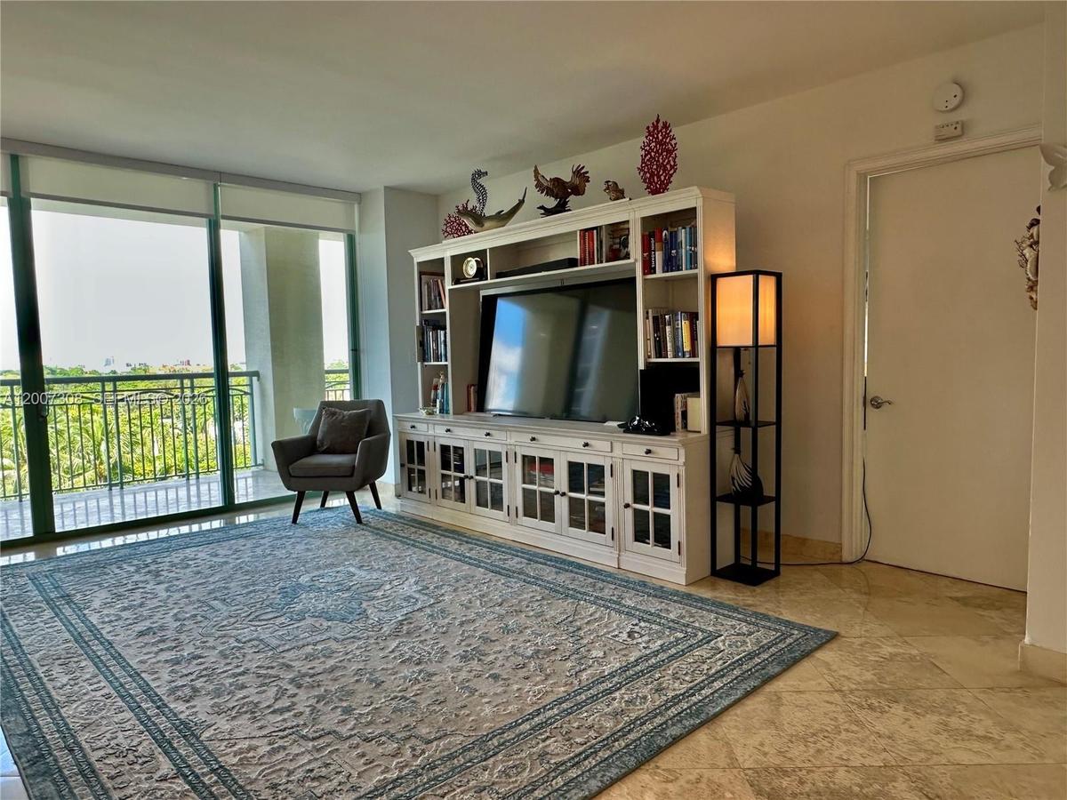 Living area featuring floor-to-ceiling glass sliding doors, stone-finish flooring, and a large built-in white entertainment center with glass-paneled 