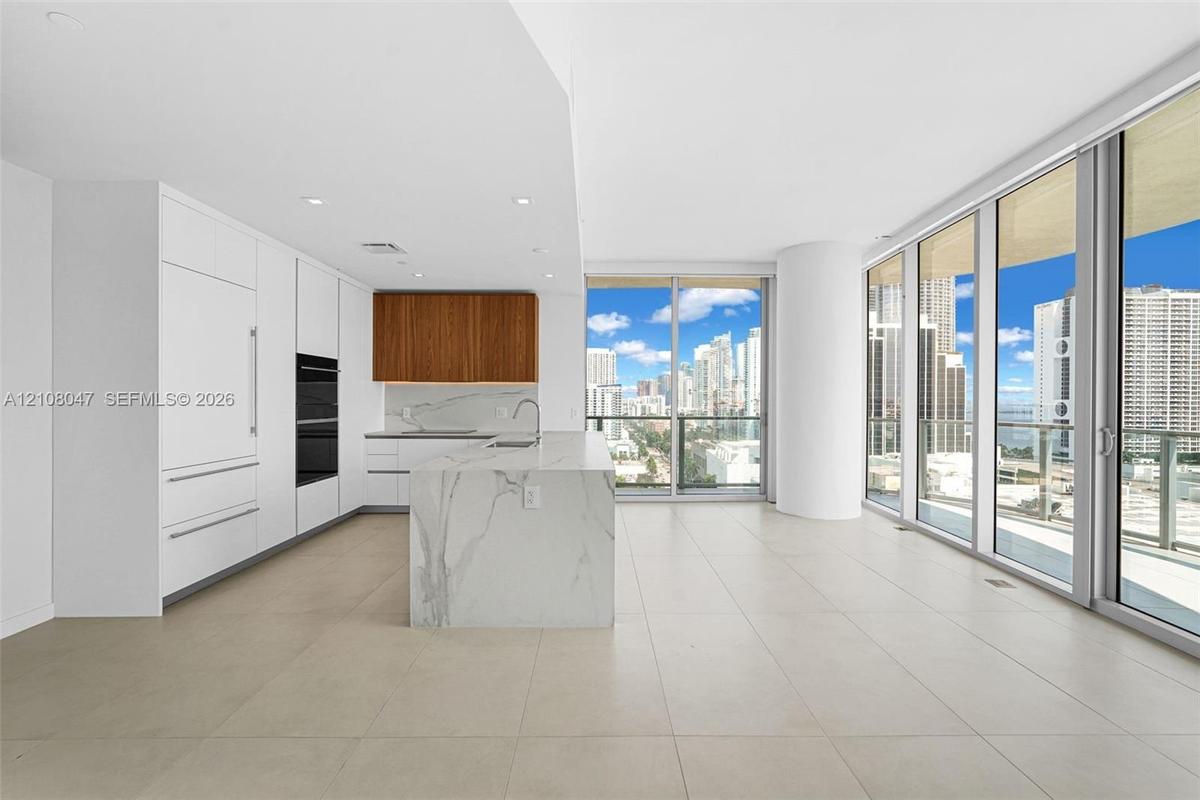 Open-concept kitchen with a waterfall island, integrated appliances, and wood-finish cabinetry