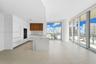 Open-concept kitchen with a waterfall island, integrated appliances, and wood-finish cabinetry