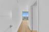 Hallway featuring wood-finish flooring, crisp white walls, and floor-to-ceiling glass paneling with an exterior railing