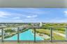 Full-height glass balcony enclosure with metal framing, wood-finish flooring, and expansive panoramic scenery including a central lagoon