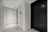 Recessed ceiling lighting illuminates the corridor, featuring a black elevator entrance, light-toned wall finishes, and square tile flooring
