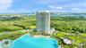 High-rise residential tower featuring floor-to-ceiling glass windows, wraparound balconies, an expansive crystalline lagoon, landscaped grounds, and p