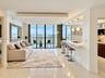 Open-concept space featuring floor-to-ceiling windows, polished tile flooring, a tiered tray ceiling with recessed lighting, and a breakfast bar with 