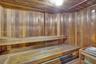 Sauna featuring tongue-and-groove wood paneling, multi-level slatted benches, and a built-in heating unit