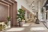 Grand lobby featuring high ceilings, stone tile flooring, geometric light fixtures, wood-paneled accent wall with integrated lighting, and a stone-cla