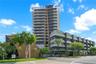 Contemporary high-rise architecture featuring glass-railed private balconies, a multi-story facade with dark paneling, and an attached low-rise struct